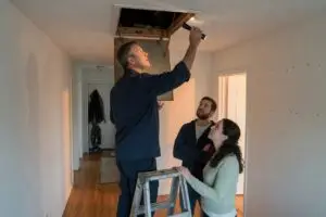 home inspection checklist - licensed home inspector checking the attic hatch while a young couple watch